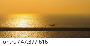 Manama, Bahrain - Jan 08 2024, Panorama of the sea at dawn, sunrise, morning, a small boat sailing along the long pier, Manama, Bahrain. Стоковое фото, фотограф Сергей Богомяко / Фотобанк Лори