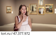 Beautiful woman in a gallery. European student visits a museum with interest and studies paintings and art. Стоковое видео, видеограф Яков Филимонов / Фотобанк Лори