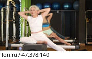 Senior woman sitting on box set equipment reformer performs for abdominal muscles. Стоковое видео, видеограф Яков Филимонов / Фотобанк Лори