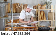 Bakery employee in apron examines documents, ponders debt restructuring. Стоковое видео, видеограф Яков Филимонов / Фотобанк Лори