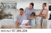 Disgruntled father carefully reads documents. Whole family stands in fear in the background. Стоковое видео, видеограф Яков Филимонов / Фотобанк Лори