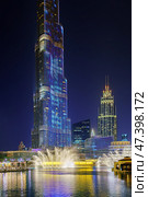 Dubai, United Arab Emirates - Jan 19 2024, view of the pool with dancing fountains and the Burj Khalifa tower, at nighttime, with illumination and street light, Dubai, UAE. Редакционное фото, фотограф Сергей Богомяко / Фотобанк Лори