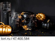 A mysterious black skull with golden roses and pumpkins for a Halloween or Day of the dead party on a black grunge background. Стоковое фото, фотограф Photojuli / Фотобанк Лори