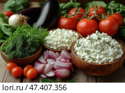 A natural, fresh still life of farm produce. Wooden bowls contain cottage cheese garnished with dill sprigs, and next to it are sliced ​​red onions, a bunch of fresh dill, whole tomatoes and cherry tomatoes, eggplant, white onions and spinach leaves. All the ingredients are laid out on a wooden surface, which gives the picture a warm, rustic and eco-friendly character. The image conveys a feeling of freshness, home comfort and healthy eating. Стоковое AI-изображение, AI-художник Анна Кривицкая / Фотобанк Лори
