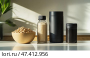 Fitness essentials for a healthy lifestyle including a water bottle and bowl. Три предмета первой необходимости для фитнеса, выставленные на столе: чаша с овсянкой, бутылка с водой и два контейнера для питания, освещенные естественным солнечным светом в минималистской обстановке. Стоковое AI-изображение, AI-художник Katsiaryna Repich / Фотобанк Лори