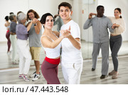 Happy caucasian guy and girl practising paired latin dance in dance studio. Стоковое фото, фотограф Яков Филимонов / Фотобанк Лори