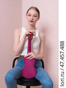 Calm female musician with ukulele held upright, sitting on bar stool, looking confidently at camera. Стоковое фото, фотограф А. А. Пирагис / Фотобанк Лори