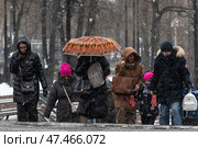 Прохожие закрывают лицо капюшонами от порывов ветра и мокрого снега на Тверской улице во время снегопада в центре города Москвы, Россия. Редакционное фото, фотограф Николай Винокуров / Фотобанк Лори
