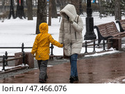 Женщина закрывает лицо капюшоном от порывов ветра и мокрого снега на Тверской улице во время снегопада в центре города Москвы, Россия. Редакционное фото, фотограф Николай Винокуров / Фотобанк Лори
