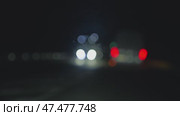A blurred view of night traffic, emphasized by bright bokeh effects from car headlights. View from the interior of a car driving on the highway. Стоковое видео, видеограф Воловодов Владимир / Фотобанк Лори