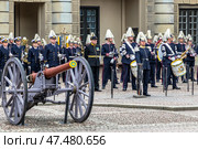 STOCKHOLM, SWEDEN - APRIL 30, 2018: Military musicians from The Royal Swedish Navy Band and The Royal Swedish Army Band stand waiting next to a vintage cannon during the 72nd birthday celebrations of King Carl XVI Gustaf at the Royal Palace in Stockholm. Редакционное фото, фотограф Сергей Комаров / Фотобанк Лори