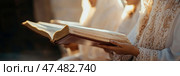Ancient Wisdom: Open Book of Scriptures held by a Person in Ceremonial Dress. Стоковое AI-изображение, AI-художник Данила Большаков / Фотобанк Лори