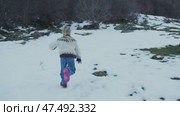 Blonde girl wearing white and brown sweater with pink boots running through snowy landscape of Pyrenees National Park, capturing childhood freedom and joyful winter exploration. Стоковое видео, видеограф Данил Руденко / Фотобанк Лори