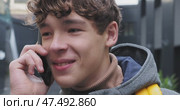 Young person messaging on smartphone, grinning while listening amid rainy urban backdrop, radiating joyful digital connectivity. Стоковое видео, видеограф Данил Руденко / Фотобанк Лори