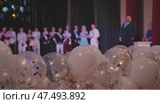 Festive white and transparent balloons scattering gold and silver confetti across graduation stage backdrop. Стоковое видео, видеограф Mikhail Davidovich / Фотобанк Лори