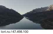 Aerial - Serene mountain lake reflecting golden sunset sky, crystal clear waters mirroring rugged Spanish Pyrenees wilderness with tranquil landscape glowing. Стоковое видео, видеограф Данил Руденко / Фотобанк Лори
