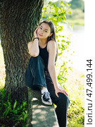 Serene student enjoying a tranquil moment in nature, surrounded by lush greenery and embracing the peacefulness of the outdoors. Стоковое фото, фотограф Mikhail Davidovich / Фотобанк Лори