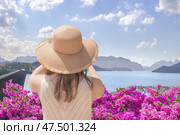 Woman tourist traveler in a wide-brimmed hat takes pictures of Lake Checo Lan and Dam from viewing point, rear view. Thai Tourist Spots such as Rachaphrapha Dam in Khao Sok Park in Phang Nga Province. Стоковое фото, фотограф Владимир Разгуляев / Фотобанк Лори