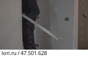 Apartment renovation. A man holds a metal rule in his hands, measuring the walls. Стоковое видео, видеограф Darya Komarova / Фотобанк Лори