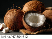 Fresh coconuts displayed on a dark surface in a kitchen setting. Свежие кокосы на темной поверхности в кухонном интерьере. Стоковое AI-изображение, AI-художник Katsiaryna Repich / Фотобанк Лори