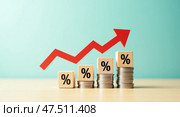 Declining interest rates concept with wooden blocks coins and red zigzag arrow. Стоковое AI-изображение, AI-художник Андрей Бакусов / Фотобанк Лори