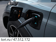 Charging an electric vehicle at a station during the day in a modern city. Зарядка электромобиля на станции в дневное время в современном городе. Стоковое AI-изображение, AI-художник Katsiaryna Repich / Фотобанк Лори