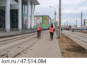 Россия, Пермь, март 2025г. Курьеры сервисов доставки Самокат на велосипеде и Яндекс пешком, доставляют заказы. Редакционное фото, фотограф Ирина Старкова / Фотобанк Лори