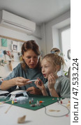 Mother and daughter conduct hands-on science experiment, mixing resin and pigments while observing reaction under UV light. Safe chemistry activities spark curiosity and learning. Стоковое видео, видеограф Енваев Андрей / Фотобанк Лори