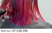 Close-up of vibrant pink hair ends resting on a black cape. Стоковое видео, видеограф Elena Grishina / Фотобанк Лори