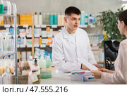 Male pharmacist helps girl buy medicine - he reads the prescription and compares it with data on computer. Стоковое фото, фотограф Яков Филимонов / Фотобанк Лори
