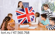 Positive female teacher discussing with preteens students state flag of Great Britain in auditory of middle school. Стоковое фото, фотограф Яков Филимонов / Фотобанк Лори