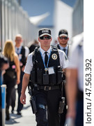 Security guard patrolling a busy public area during the daytime. Стоковое AI-изображение, AI-художник Юрий Поздников / Фотобанк Лори