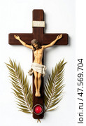 Crucifix With Jesus Figure, Red Candle, and Palm Leaves Arranged on a Clean White Background for Spiritual Reflection and Worship. Стоковое AI-изображение, AI-художник Sergey Grishin / Фотобанк Лори