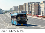 Moscow, Russia - 08.26.2024: Blue electrobus drives down the street in Moscow, front side view. Electric bus in motion. Moscow transport. Редакционное фото, фотограф Ирина Михайличенко / Фотобанк Лори