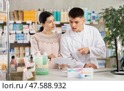 Male pharmacist helps girl buy medicine - he reads the prescription and compares it with data on computer. Стоковое фото, фотограф Яков Филимонов / Фотобанк Лори