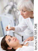 Professional mature female cosmetologist doing needleless high frequency mesotherapy in spa center. Non-invasive skin rejuvenation procedure. Стоковое фото, фотограф Яков Филимонов / Фотобанк Лори