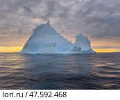 A huge high breakaway glacier drifts in the southern ocean off the coast of Antarctica at sunset, the Antarctic Peninsula, the Southern Arctic Circle, azure water, cloudy weather. Стоковое фото, фотограф Vladimir Drozdin / Фотобанк Лори