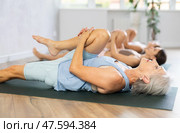 Three generations of women do preparatory stretching, lying on back and benting one leg at knee. Стоковое фото, фотограф Яков Филимонов / Фотобанк Лори