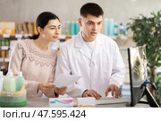 Male pharmacist helps girl buy medicine - he reads the prescription and compares it with data on computer. Стоковое фото, фотограф Яков Филимонов / Фотобанк Лори