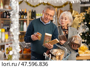 Preparing for Christmas celebration - elderly husband and wife buying nougat, panettone and chocolate. Стоковое фото, фотограф Яков Филимонов / Фотобанк Лори