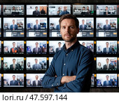 Мужчина стоит перед стеной из мониторов, на которых отображаются различные изображения людей. Стоковое AI-изображение, AI-художник Ярославский Максим / Фотобанк Лори