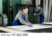 Girl glazer employee in blue overall works in glass processing shop. Стоковое фото, фотограф Яков Филимонов / Фотобанк Лори