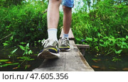 The boy goes along the bridge through the forest river. Стоковое видео, видеограф Igor Skripachev / Фотобанк Лори