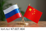 Национальные флаги России и Китая на деревянном столе. Символы стран крупным планом. Стоковое AI-изображение, AI-художник Илья Старков / Фотобанк Лори