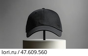 Black cap mockup displayed on a minimalistic stand in a modern setting. Черная крышка на минималистичной подставке в современном стиле. Стоковое AI-изображение, AI-художник Katsiaryna Repich / Фотобанк Лори