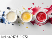 Three yogurt containers with, aligned in a row on a white background, splashes of fruit purée. три контейнера для йогурта  в ряд на белом фоне брызгами фруктового пюре. Стоковое AI-изображение, AI-художник Katsiaryna Repich / Фотобанк Лори