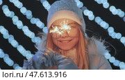 Sparklers in the hands of a girl in mittens against the background of the city's Christmas lights. Стоковое видео, видеограф Mikhail Davidovich / Фотобанк Лори