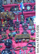 A showcase with a wide assortment of souvenirs, stationery, and decorative items made from stone and minerals. Set against a vivid magenta fabric, the display includes clocks, globes, hourglasses, pen stands, glasses, bracelets, keychains, and nameplates. A small Russian flag is also visible. Each item features rich textures and polished finishes, emphasizing craftsmanship and uniqueness. Стоковое фото, фотограф Анна Кривицкая / Фотобанк Лори