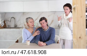Woman scolding man at kitchen while old woman calming him down. Стоковое видео, видеограф Яков Филимонов / Фотобанк Лори