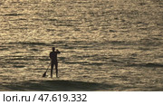 Silhouette of an athlete paddle boarding on calm ocean at golden hour. Стоковое видео, видеограф Константин Шишкин / Фотобанк Лори